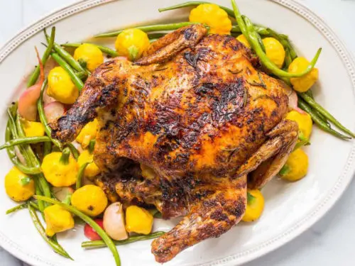 A photo of chicken recipes with a roast chicken on a bed of roast vegetables