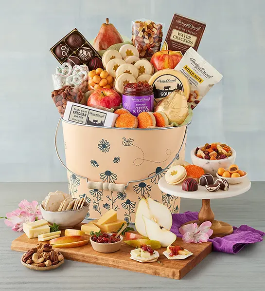 Mother's Day gift ideas with a tin full of cookies, snacks and other treats with the same items arranged in front of the tin.