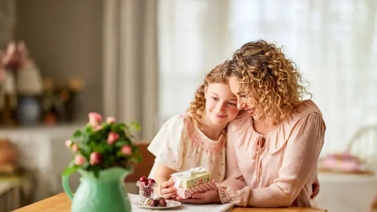 Mother's Day gift ideas with a mother and daughter cuddling and looking at gifts.