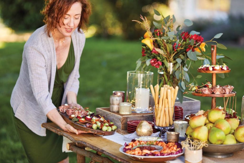 backyard party with a woman putting food out on a table.