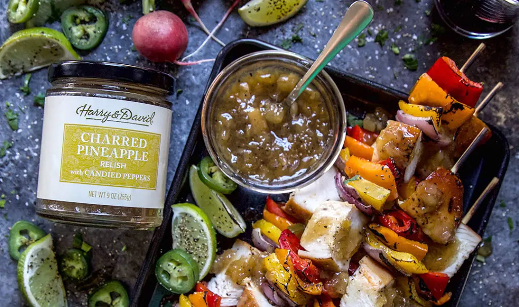 A photo of Father's Day recipes with a plate of vegetable and meat kebabs next to a jar of Harry & David's charred pineapple relish