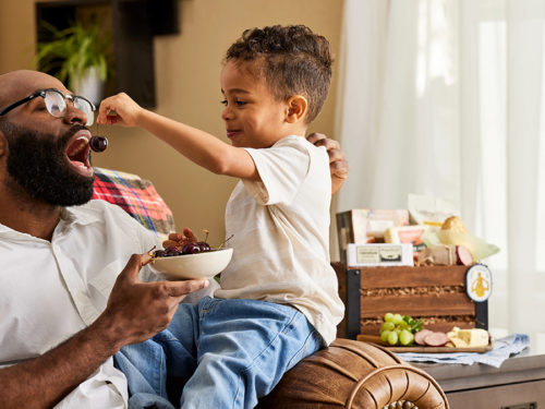 A photo of father's day gift ideas with a boy feeding a man a cherry