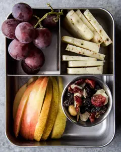 Road trip snack with fruit, cheese, and trail mix.