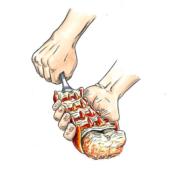 Hands using a small fork to push the lobster tail meat out of the shell.