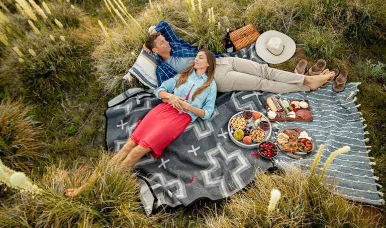 mindful vacation image -- couple napping on picnic blanket