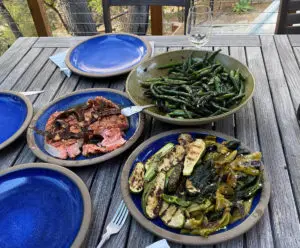 Photo of grilled salmon on a plate surrounded by plate of grilled vegetables.