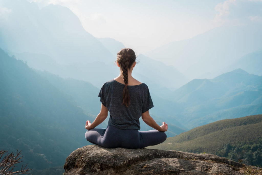 make the most of summer -- woman meditating on mountain image