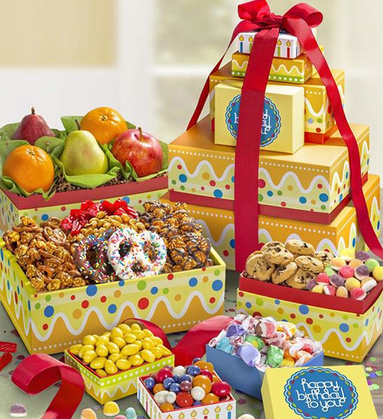 A photo of birthday gift ideas with a stack of birthday gifts next to several open boxes full of candy and fruit.