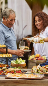 Grandparents Day image - grandchild pours wine for grandfather outside