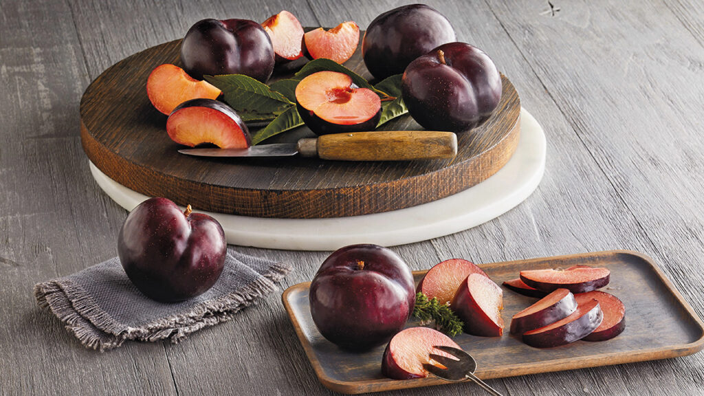Facts about plums image - whole and sliced plums on table