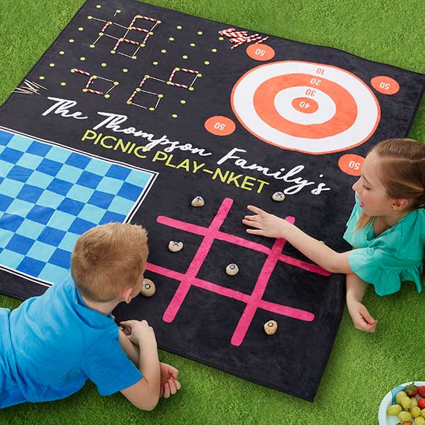 A photo of birthday gift ideas with a blanket with different game designs and two children playing tic tac toe on the blanket.