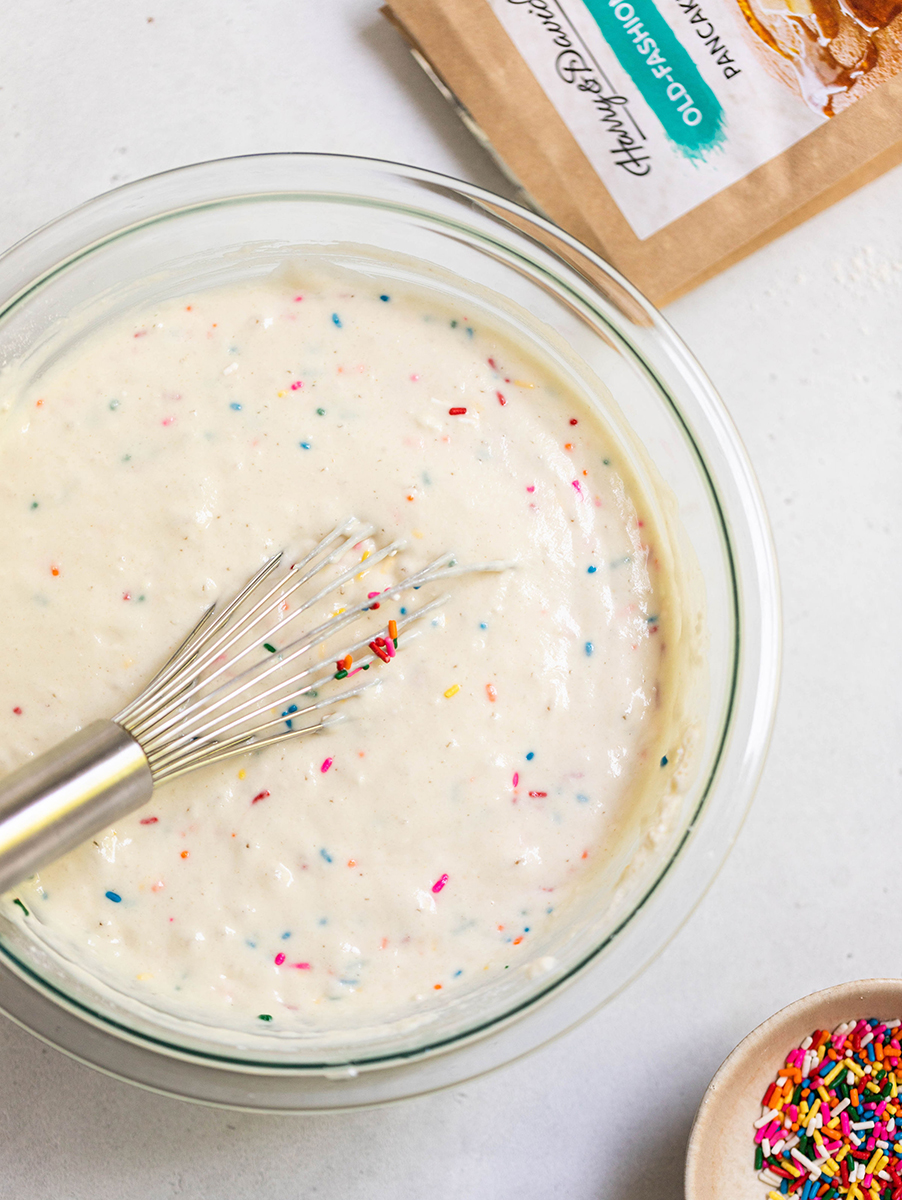A photo of confetti pancakes with a bowl of batter next to a bowl of sprinkles