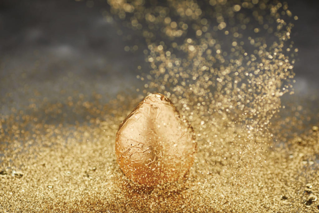 A photo of a gold pear with gold sparkles all around it