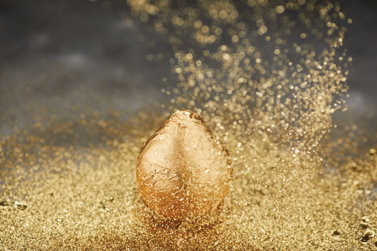 A photo of a gold pear with gold sparkles all around it
