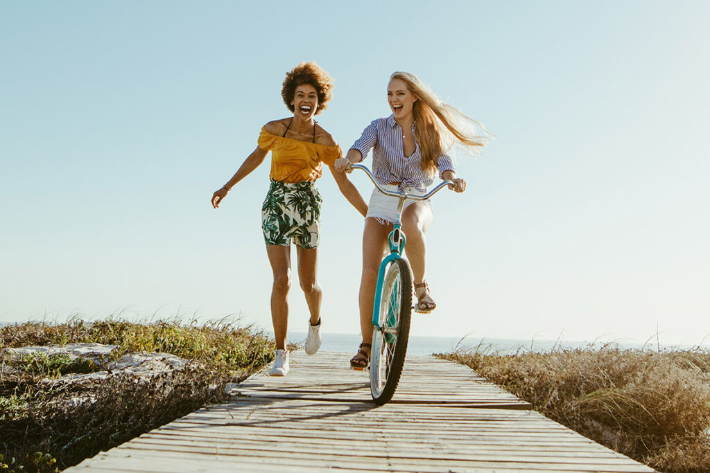 Make the most of summer with two women on a boardwalk, one riding a bike and the other running.