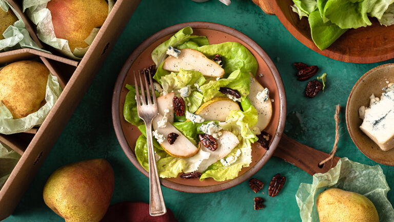 Pear and blue cheese salad in a bowl next to a box of pears.