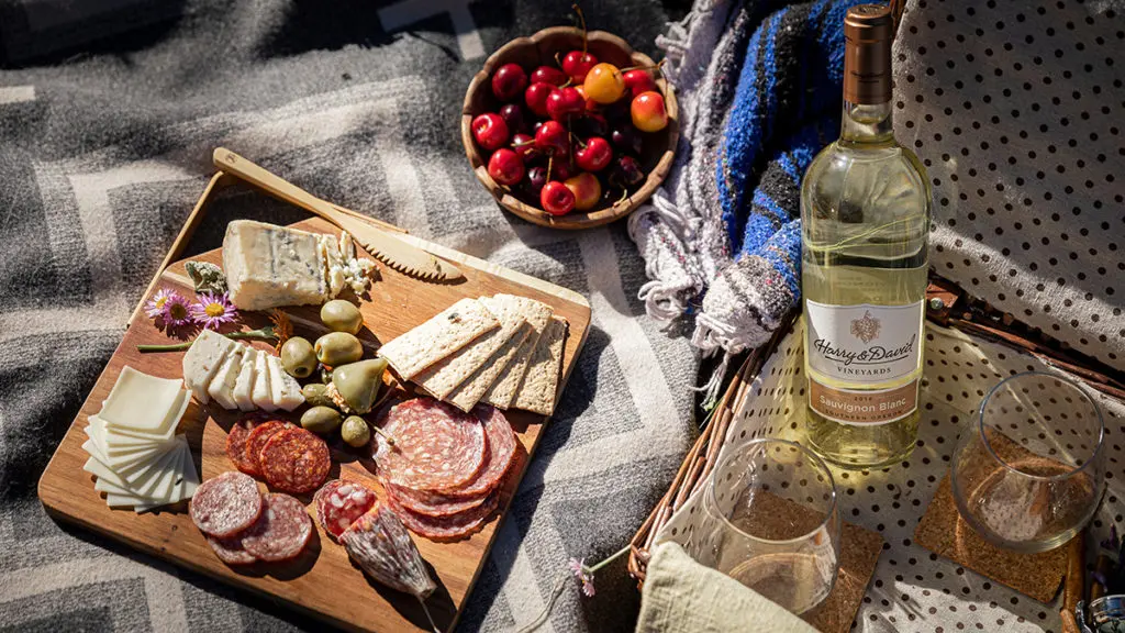 A photo of teacher gifts with a charcuterie board next to a bottle of wine.