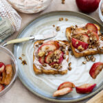 apple crisp image - apple crisp toast on a grey plate with ingredients surrounding it.