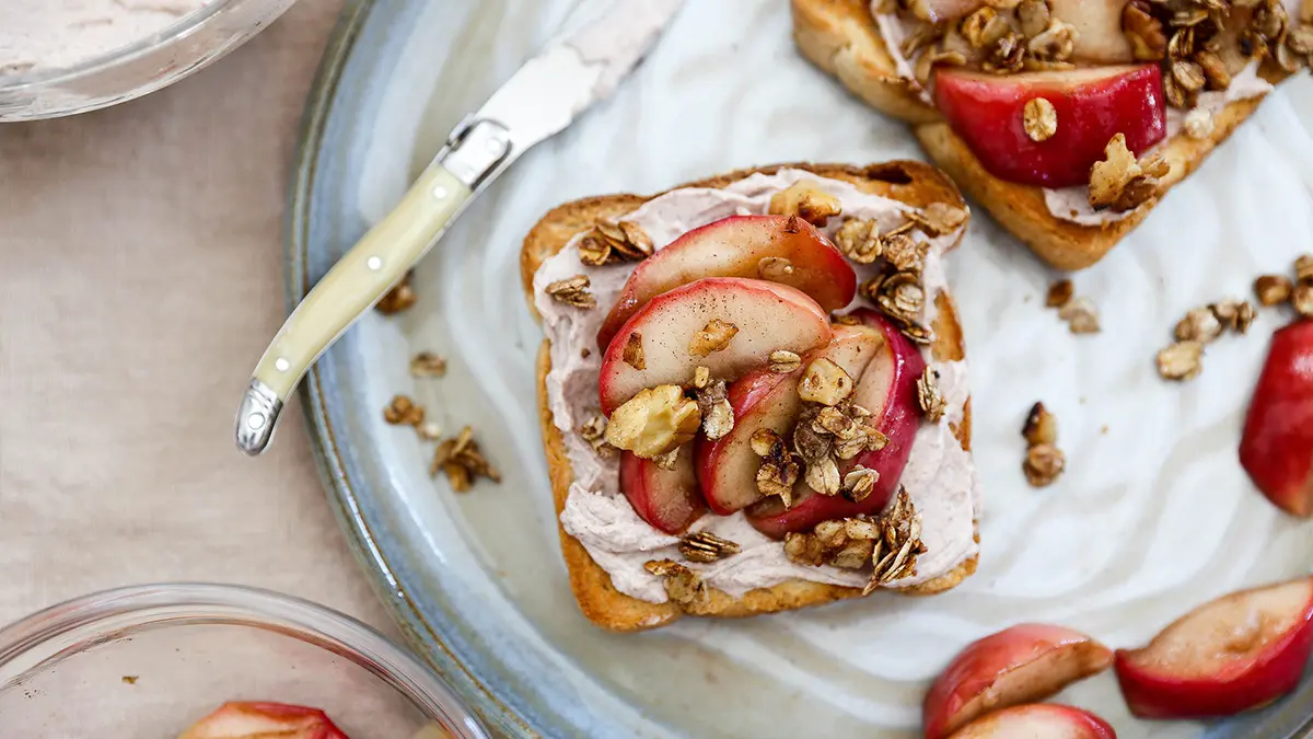 apple crisp image - apple crisp toast on a grey plate with ingredients surrounding it.