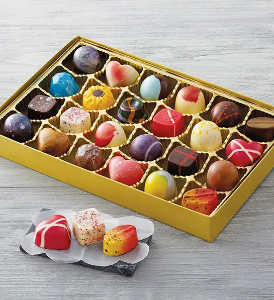 gifts for caregivers image - multicolored chocolates in a gold box with three sitting on a napkin outside and in front of the box.