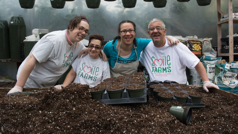 Smile farms image - group posing for photo in front of dirt 