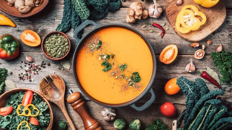 Fall flavors image - table with fall soup and vegetables on top of it.