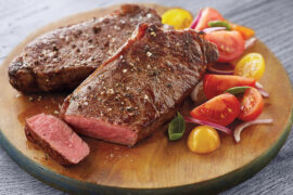 New York Strip Steak image - New York strip steak on board with fresh tomatoes