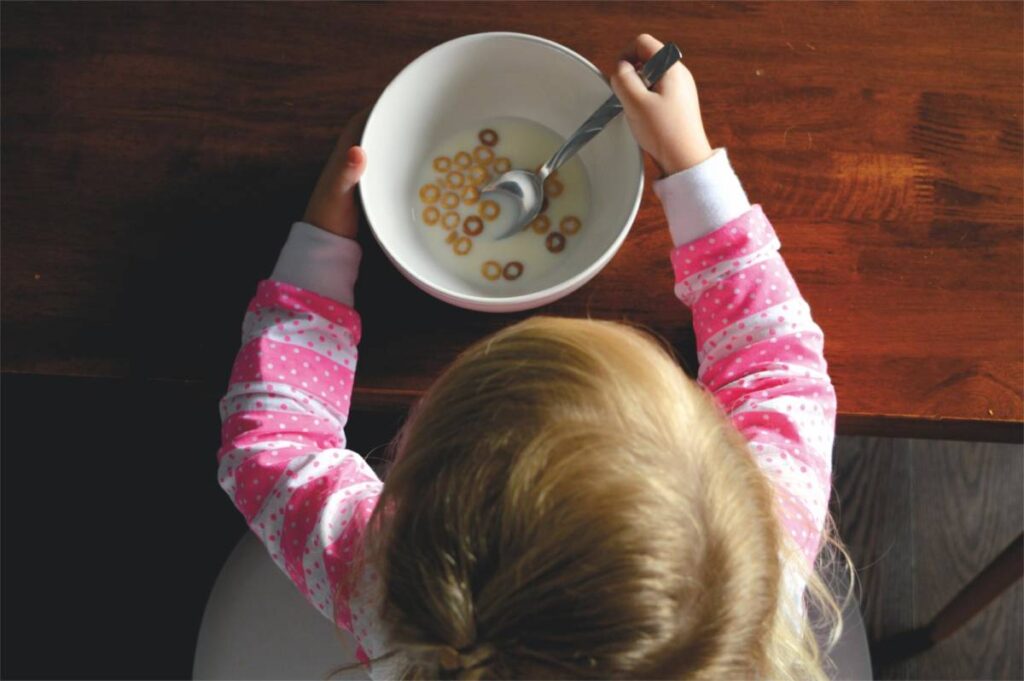 hunger and food insecurity image - overhead shot of girl eating a bowl of cereal