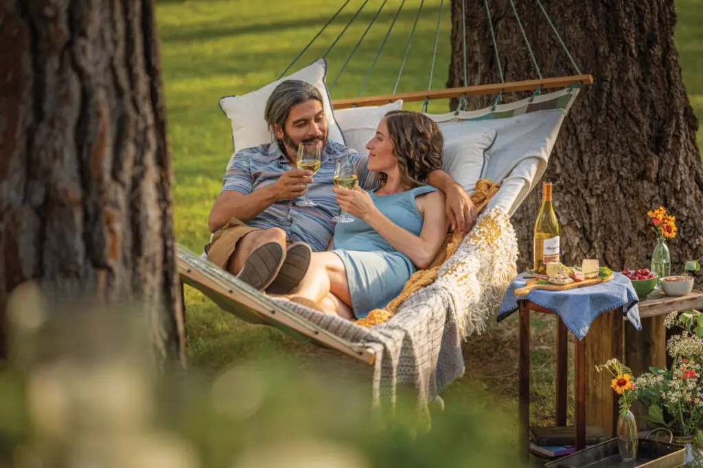 anniversary gifts by year image - couple drinking wine in hammock.