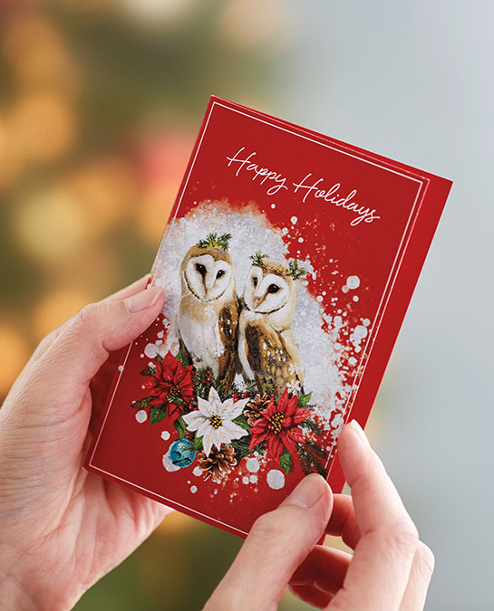 christmas quotes image - hands opening a christmas card with christmas tree in the background