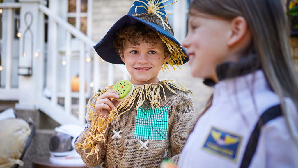 fall birthday party ideas image - child dressed as a scarecrow eating a cookie