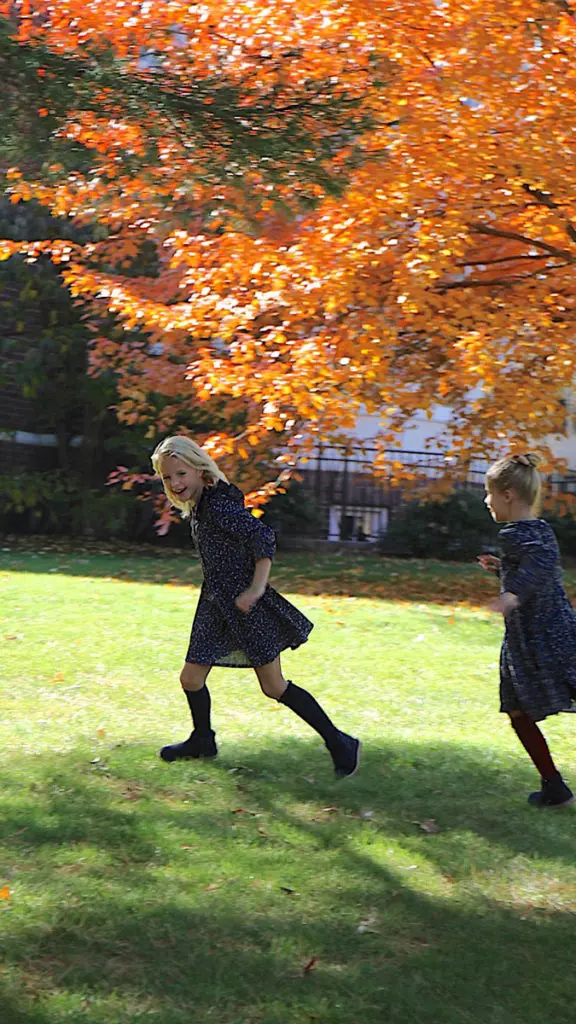 Loving fall with two girls chasing each other outside in fall leaves.
