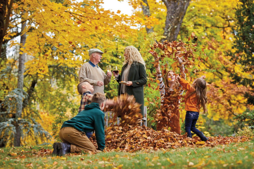 fall leaves image - kids playing in leaves with two adults in the background