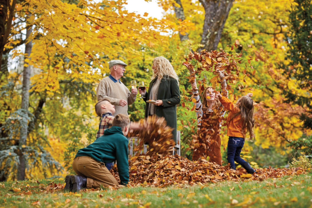 fall leaves image - kids playing in leaves with two adults in the background
