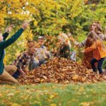 fall leaves image - kids playing in pile of leaves outside
