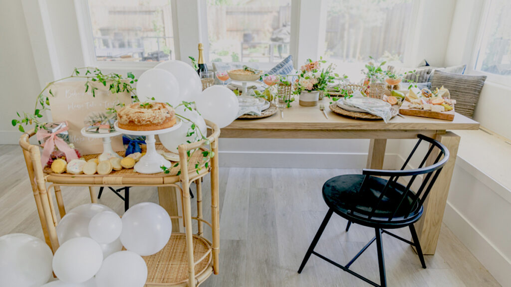 host a baby shower image - table with flowers, balloons, and food.