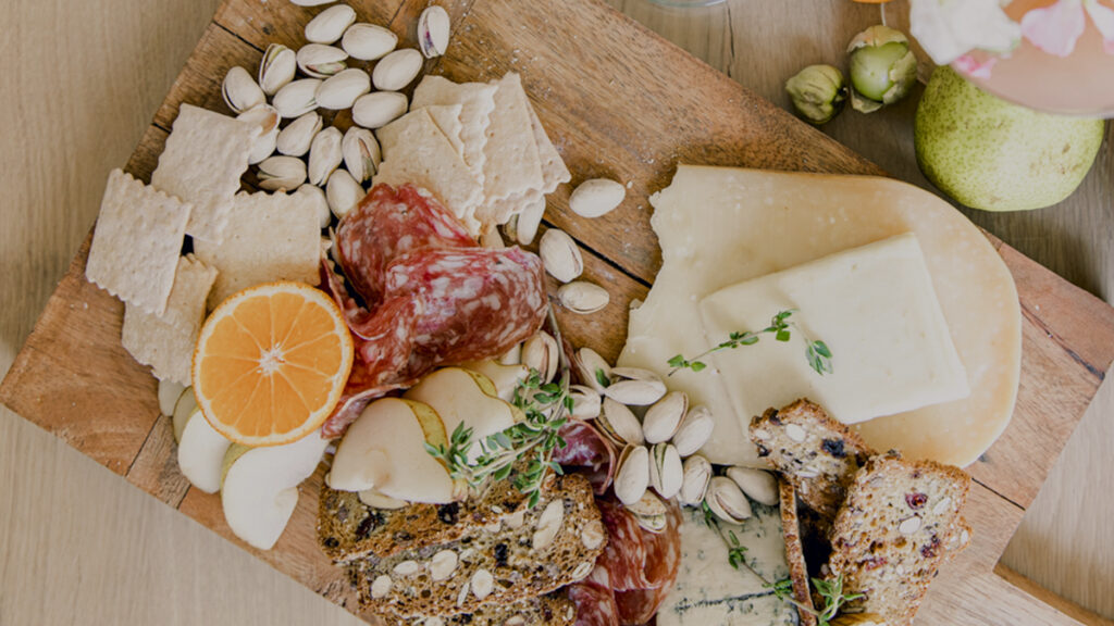 host a baby shower image - charcuterie board with crackers, fruit, cheese and meat.