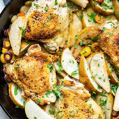 Pear braised chicken in a cast-iron skillet.