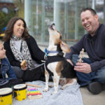 buddy the beagle image - family sitting around a beagle who is howling while they laugh