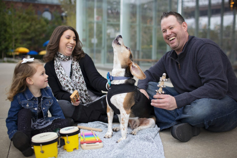 buddy the beagle image - family sitting around a beagle who is howling while they laugh