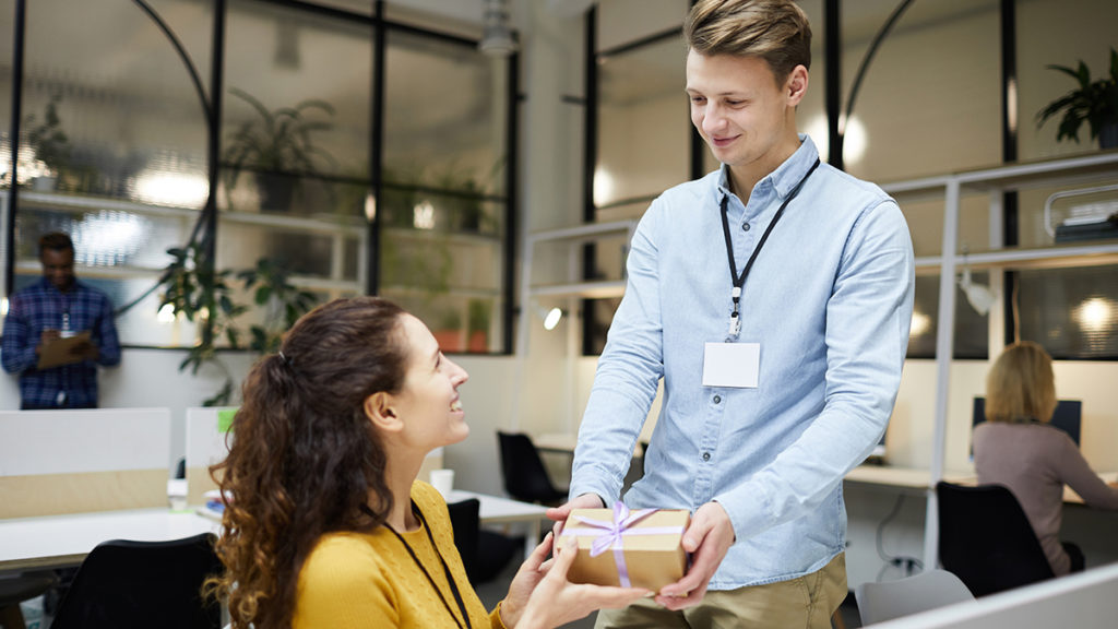 A photo of corporate gifting with a man giving his female coworker a gift
