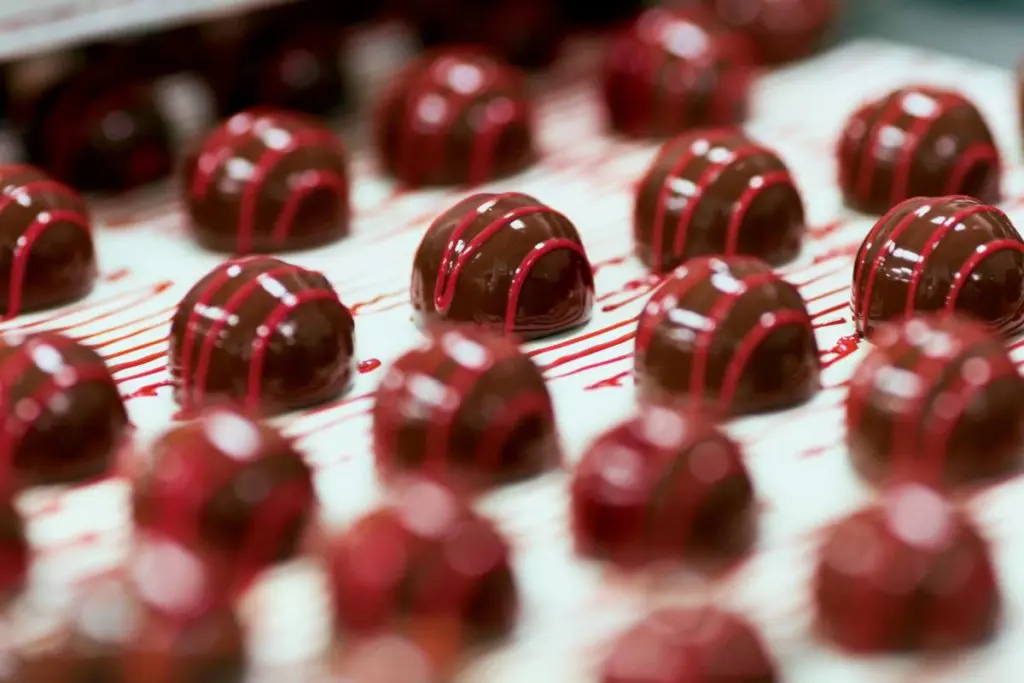 A photo of facts about chocolate. Chocolate truffles on a conveyor belt.