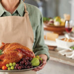 A photo of how to carve a turkey with a person holding a roast turkey on a platter