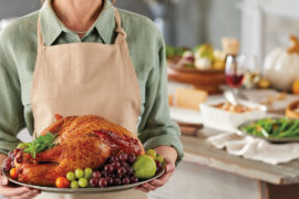A photo of how to carve a turkey with a person holding a roast turkey on a platter