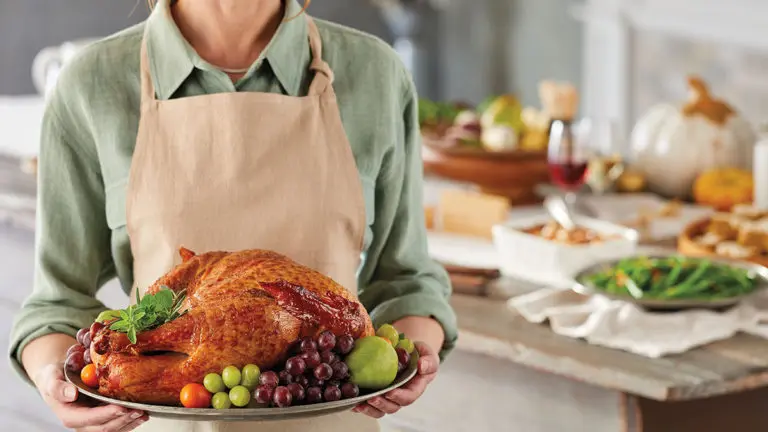 A photo of how to carve a turkey with a person holding a roast turkey on a platter