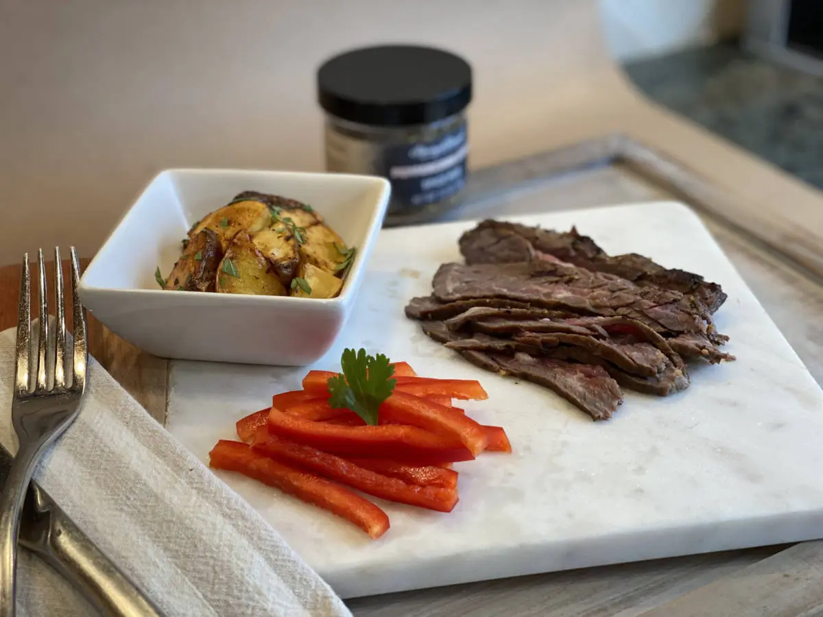 A photo of lunch box ideas, a cutting board with strips of steaks and bell pepper next to a bowl of potoates