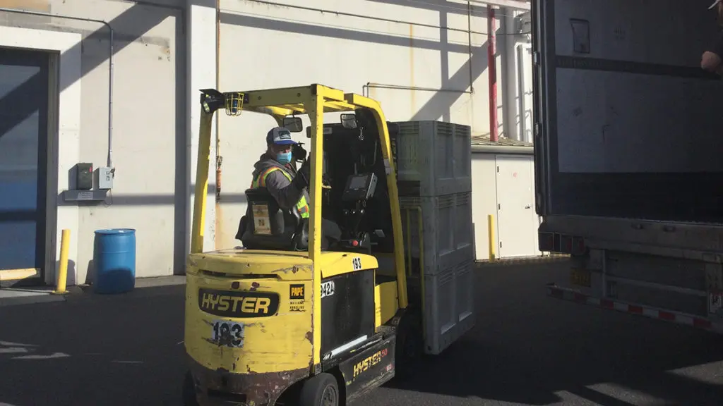 A photo of a food bank with a man on a tractor moving boxes of food.