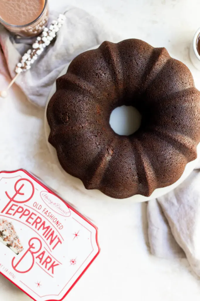 A photo of a bundt cake sitting next to a tin of peppermint bark