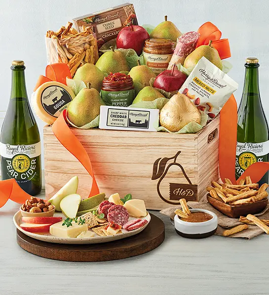 Christmas gift guide with a box of pears, cheese, crackers, and other snacks with two bottles of pear cider.