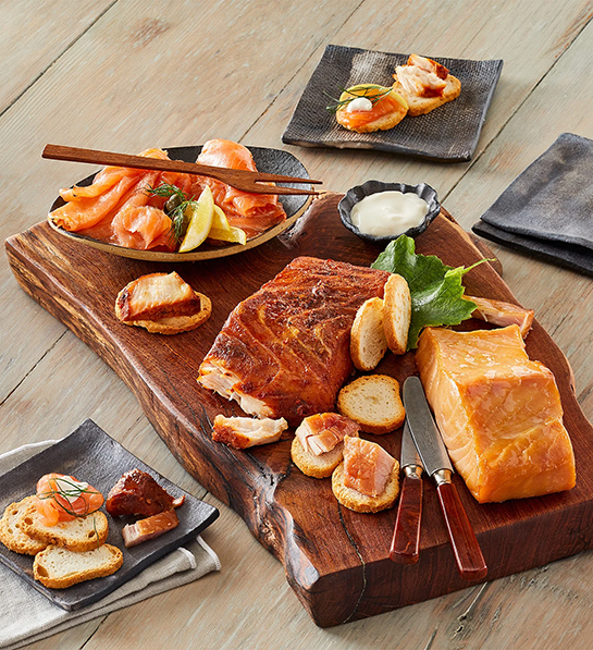 Christmas gift guide with smoked salmon and other smoked fish on a wooden board.